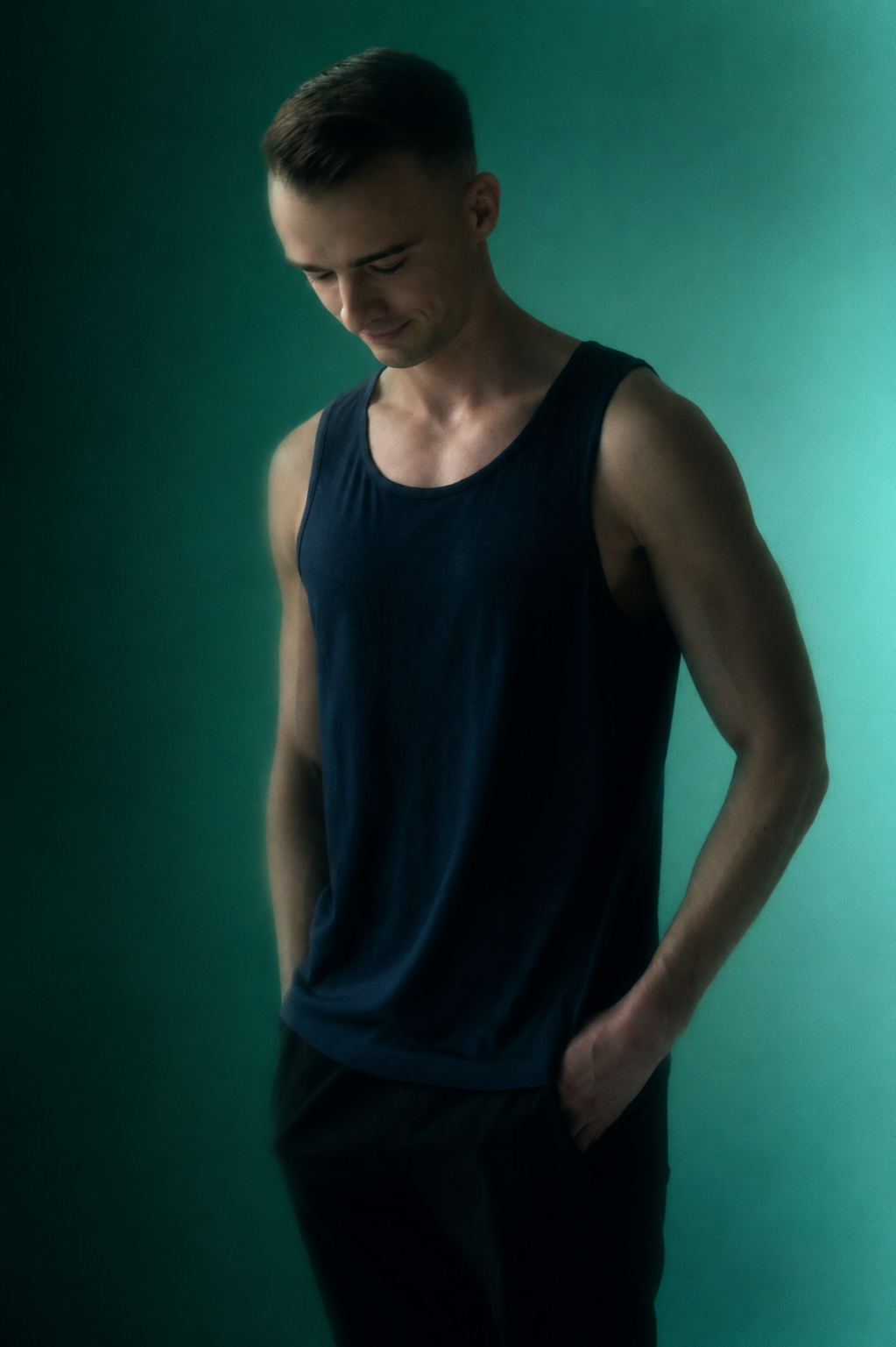 Man wearing a dark tank top against a green background