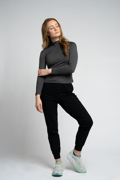 Woman wearing a gray long-sleeve top and black pants on a white background