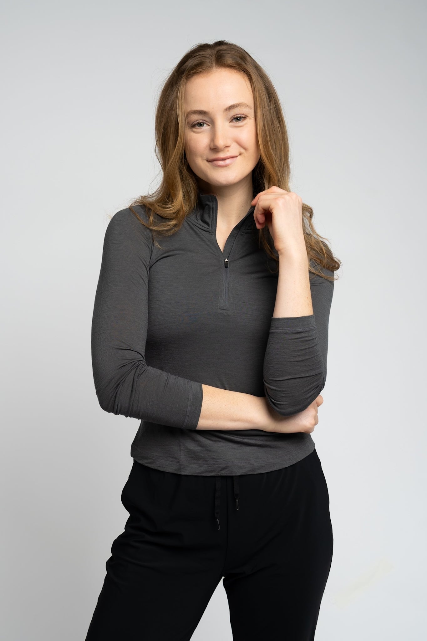 Woman wearing a gray long-sleeve top and black pants on a light gray background