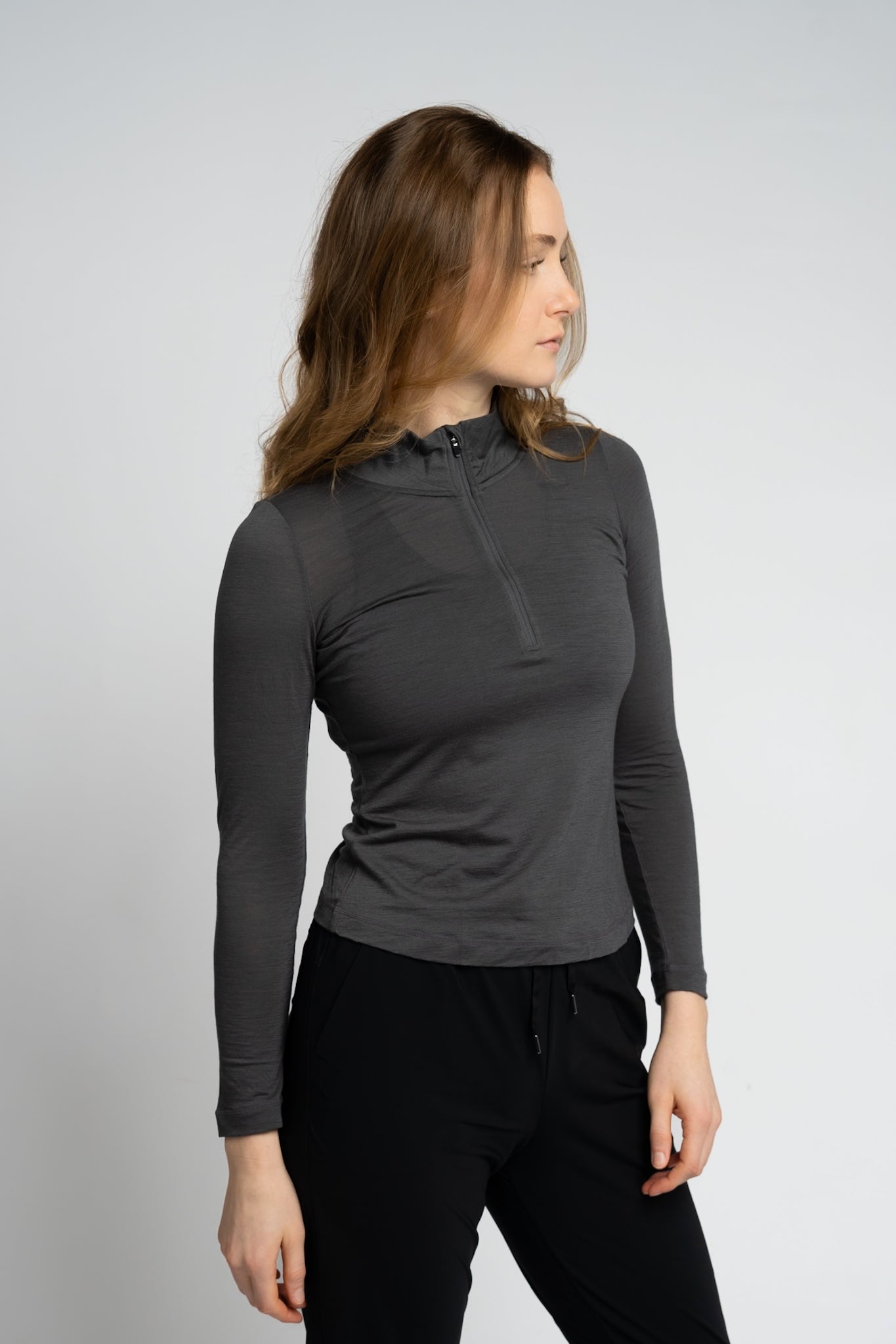 Woman wearing a dark gray long-sleeve top with a subtle pattern on a light gray background