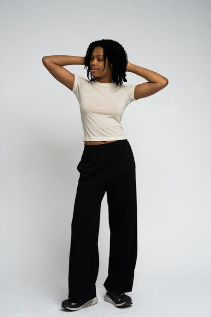 Person wearing a white t-shirt and black pants against a plain background
