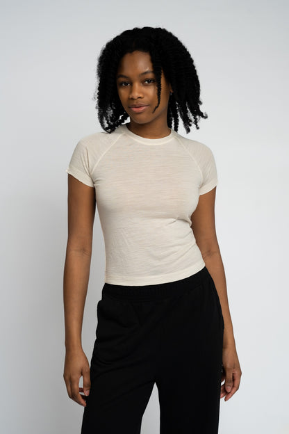 Person wearing a beige t-shirt and black pants against a white background