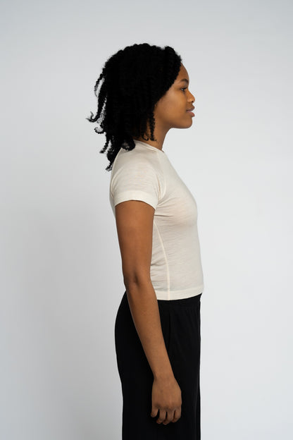 Woman wearing a white shrt and black pants against a plain background