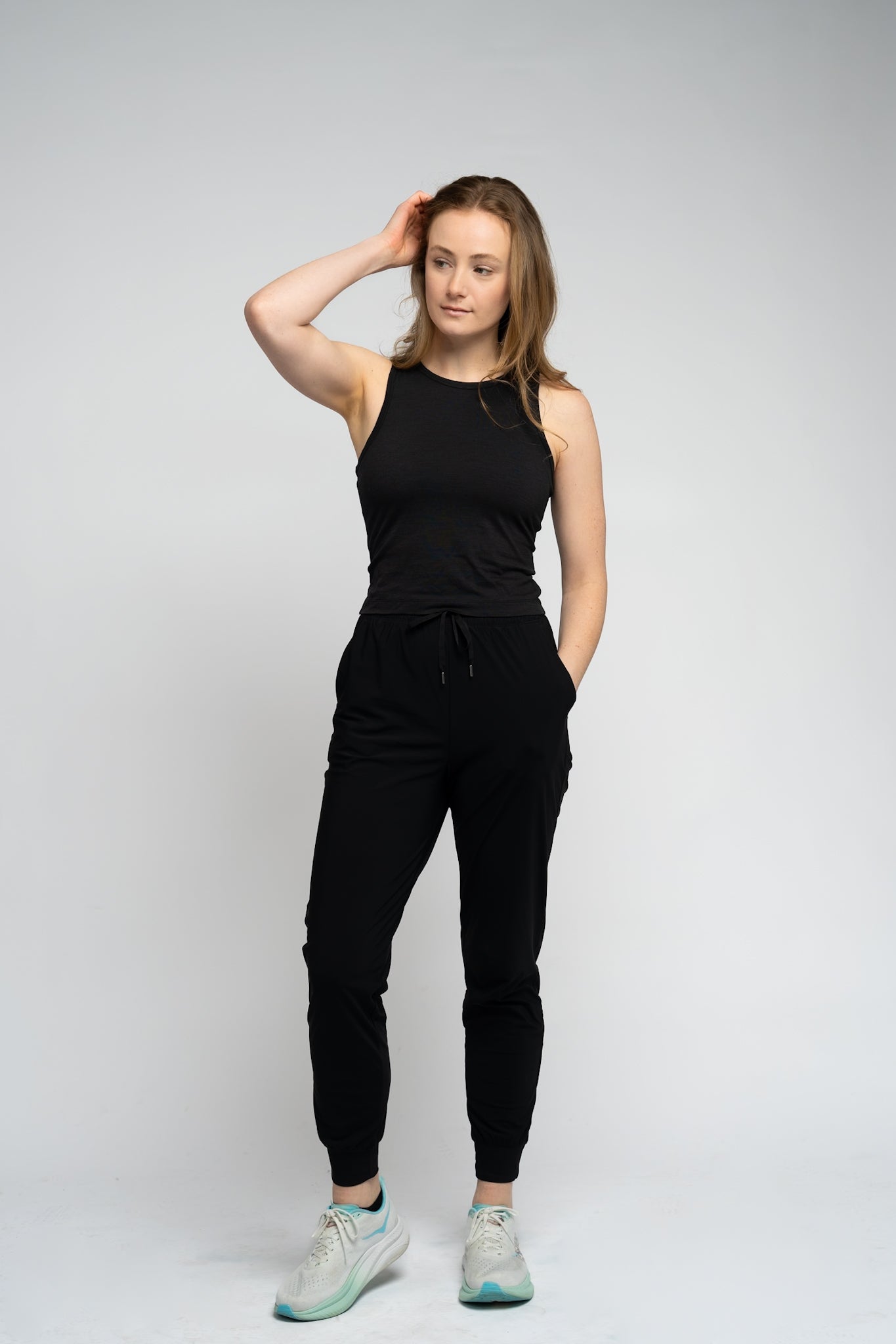 Woman wearing a black sleeveless top and black pants on a white background