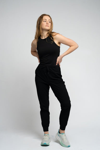 Woman wearing a black sleeveless top and black pants on a white background