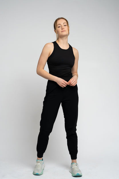 Person wearing a black tank top and black pants on a white background