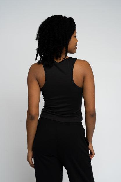 Person wearing a black sleeveless top and pants on a white background