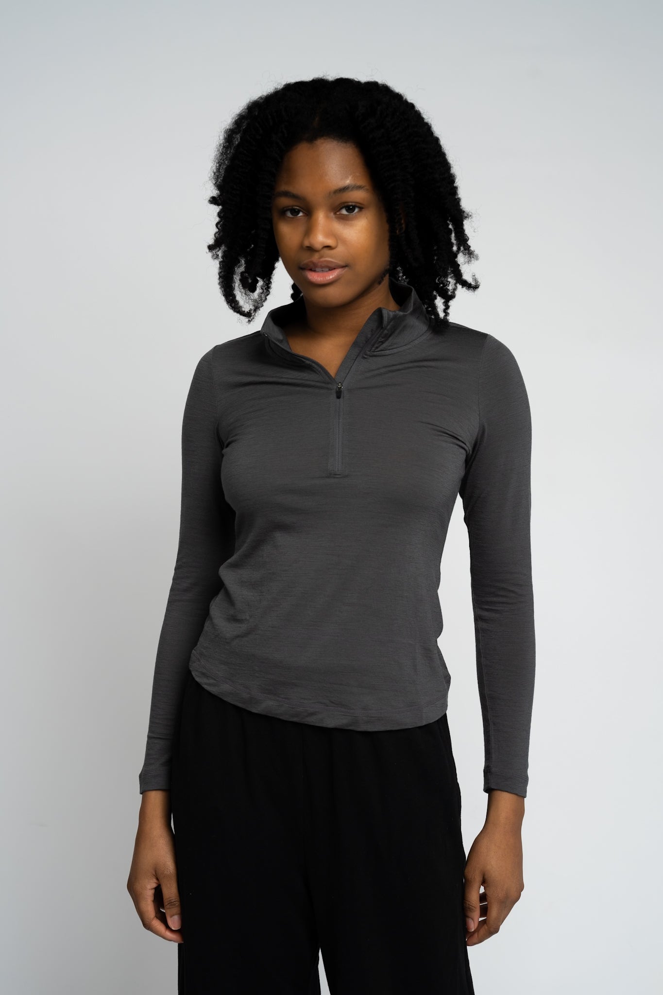 Woman wearing a gray long-sleeve shirt with a quarter zip on a white background