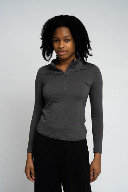 Woman wearing a gray long-sleeve shirt with a quarter zip on a white background