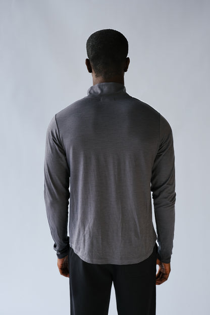 Person wearing a gray long-sleeve shirt against a plain background