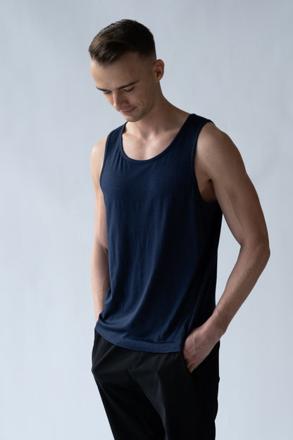 Man wearing a navy blue tank top against a light gray background