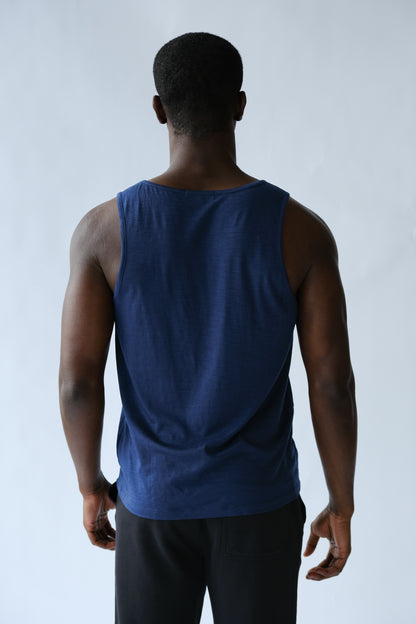Person wearing a blue tank top and black pants against a white background