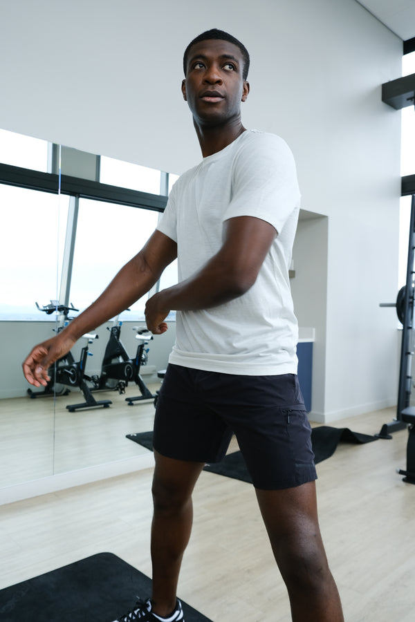 Man in a white t-shirt and black shorts standing in a gym.