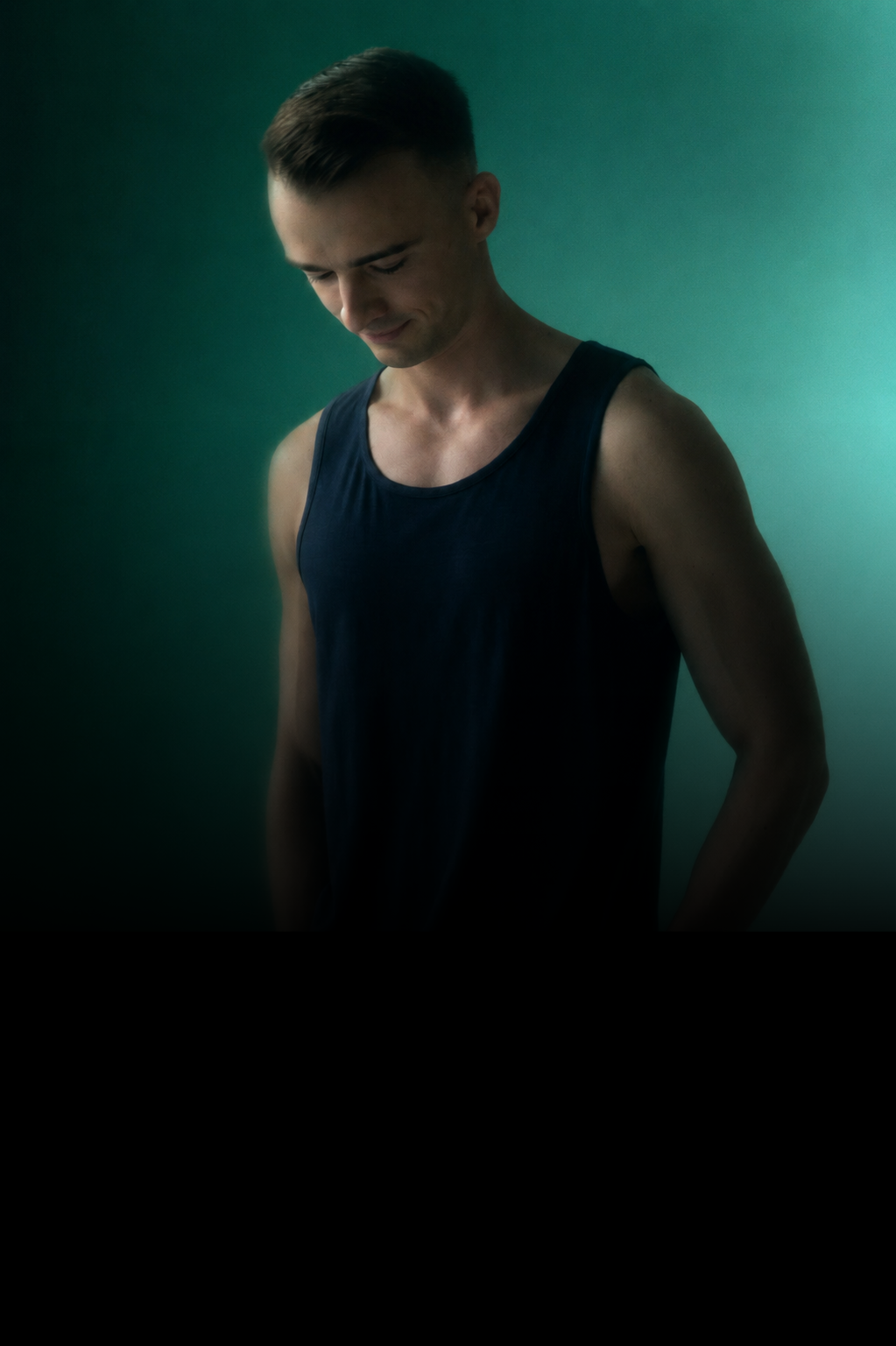 Man wearing a dark tank top against a green background